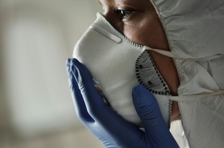 Osoba sa zaštitnim rukavicama stavlja zaštitnu masku na lice