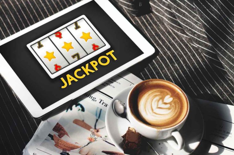 tablet sa online jackpot igrom pored bele šolje sa kapućinom