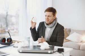 Čovek bolestan drži papirnu maramicu.