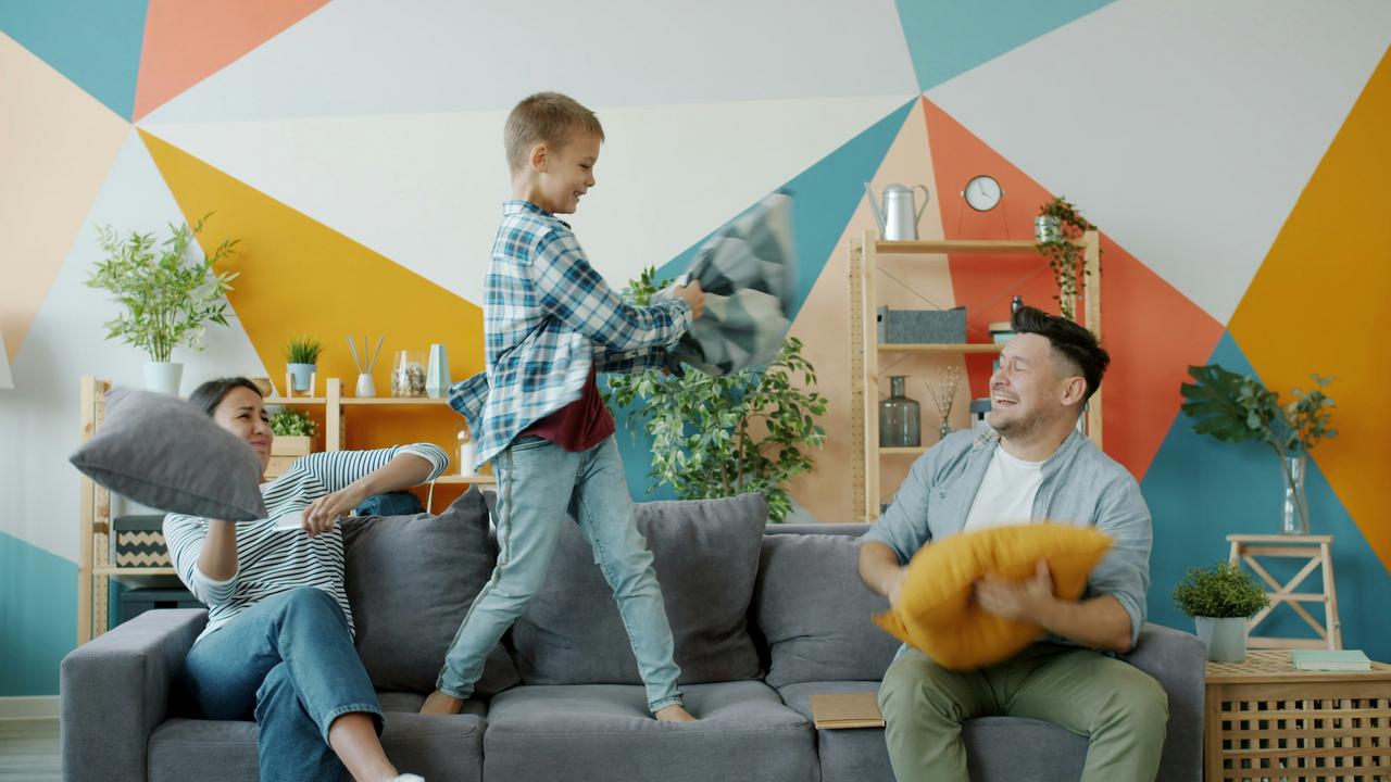 Porodica na sivom kauču u dnevnoj sobi igra se jastucima.