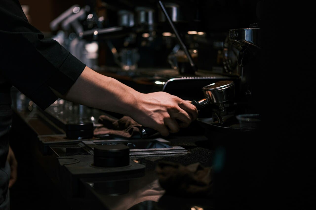 Ruka bariste drži portafilter dok ga ubacuje u espresso mašinu