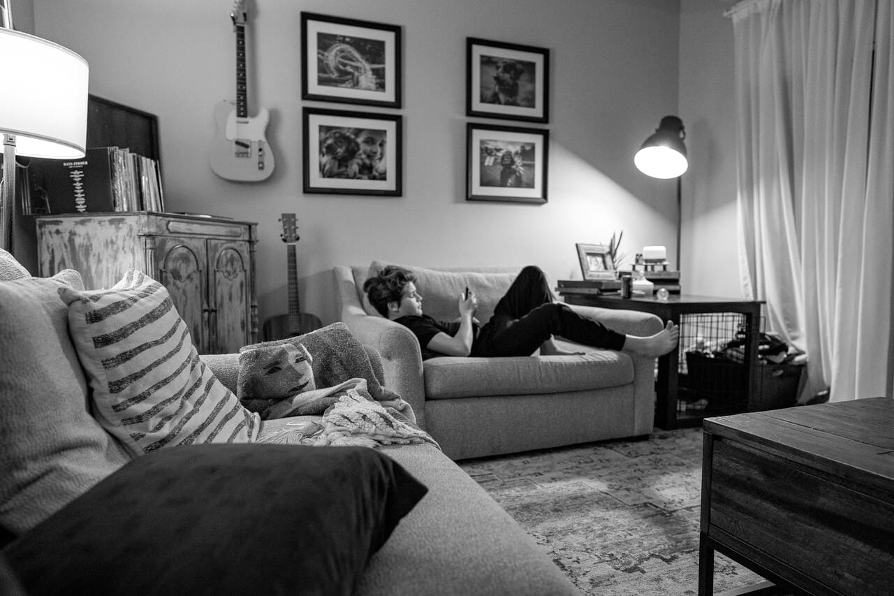 Osoba leži na kauču i gleda u telefon