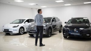 Muškarac stoji u salonu i gleda tri parkirana automobila