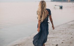 Devojka u dugoj haljini šeta po plaži